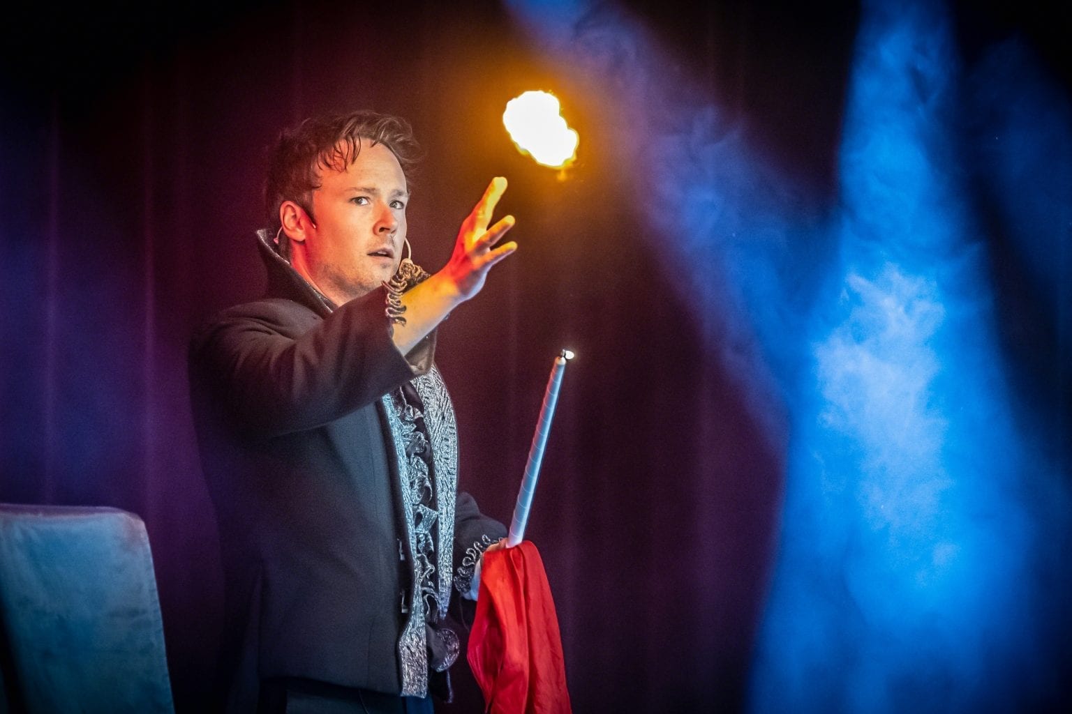 Daniel Kane på scen med en eldflamma ovanför handen i blått och lila scenljus