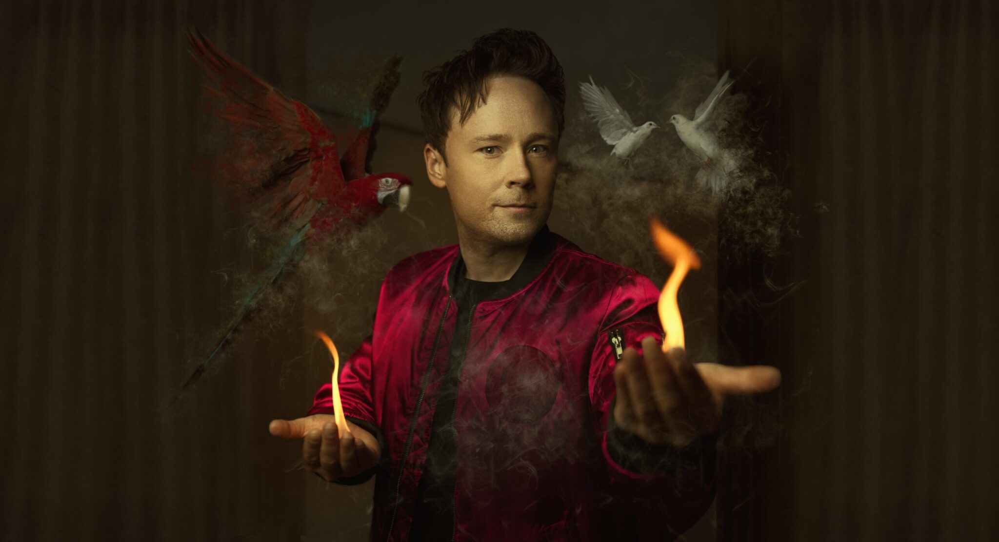 Daniel Kane i röd jacka med en papegoja och två vita duvor