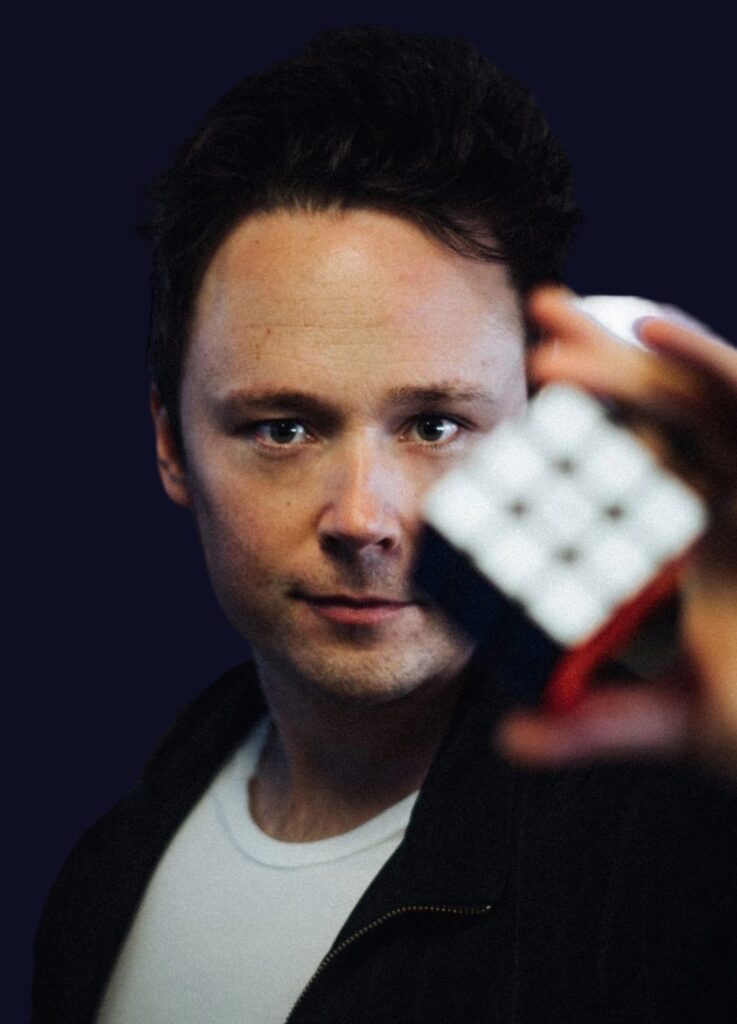 Porträtt av magikern Daniel Kane som håller fram en Rubiks kub mot kameran